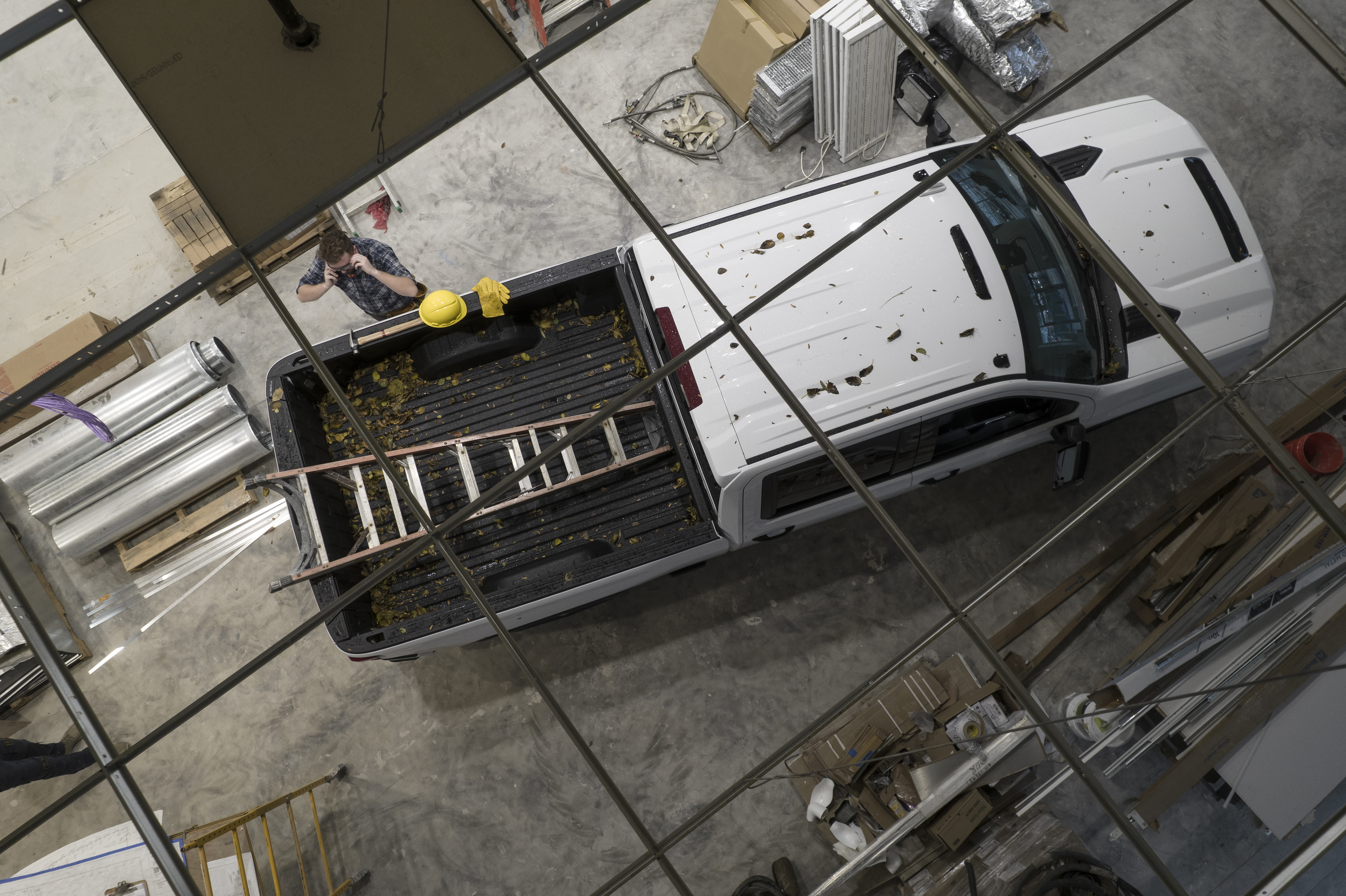 Caucasian Contractor Worker in His 30s and His White Modern Pickup Truck on a Construction Site. Ceiling Top View. Construction Industry Theme.